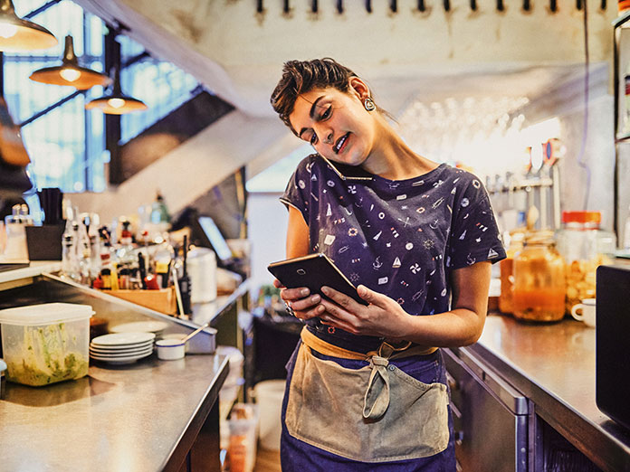 Woman on phone working in kitchen