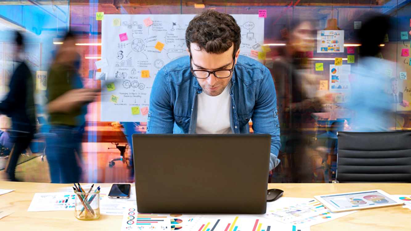 Man working on computer with whiteboard in blurry background