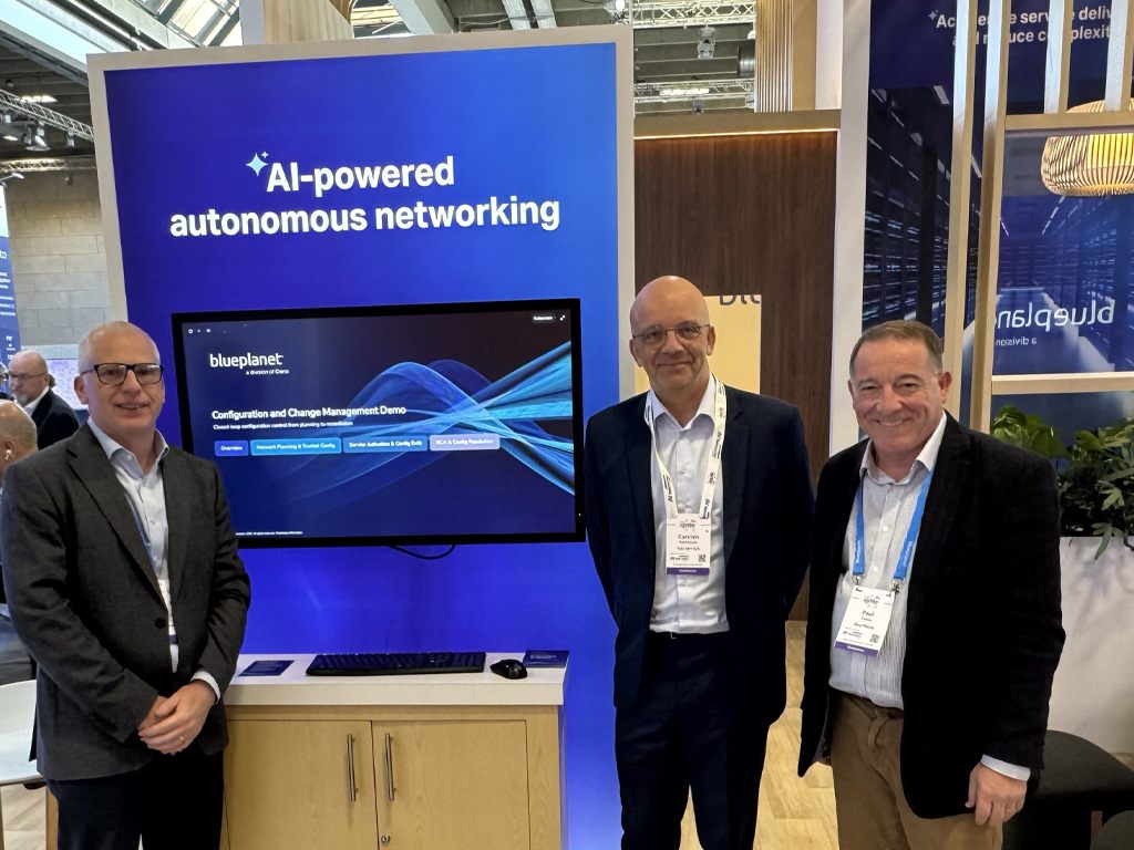 Three attendees stand beside a Blue Planet exhibit showcasing an AI-powered autonomous networking demonstration at a technology conference.