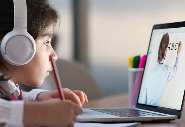 An image of a child using a laptop to learn the ABCs. The child is engaged in educational activities on the screen, highlighting the importance of bridging the digital divide through technology to ensure equal access to educational resources and opportunities.