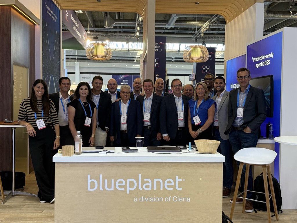 Group photo of Blue Planet team members and conference attendees gathered at the company booth during a technology industry event.