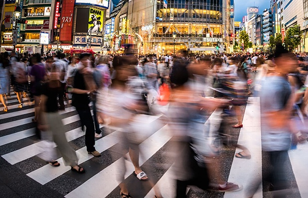 An image of a bustling street scene in Asia, featuring a crosswalk filled with pedestrians. The image captures the vibrant energy and urban life of the city, showcasing the diverse cultures and busy pedestrian activity in the region