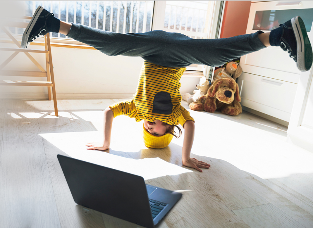 Little boy doing headstand in front of laptop