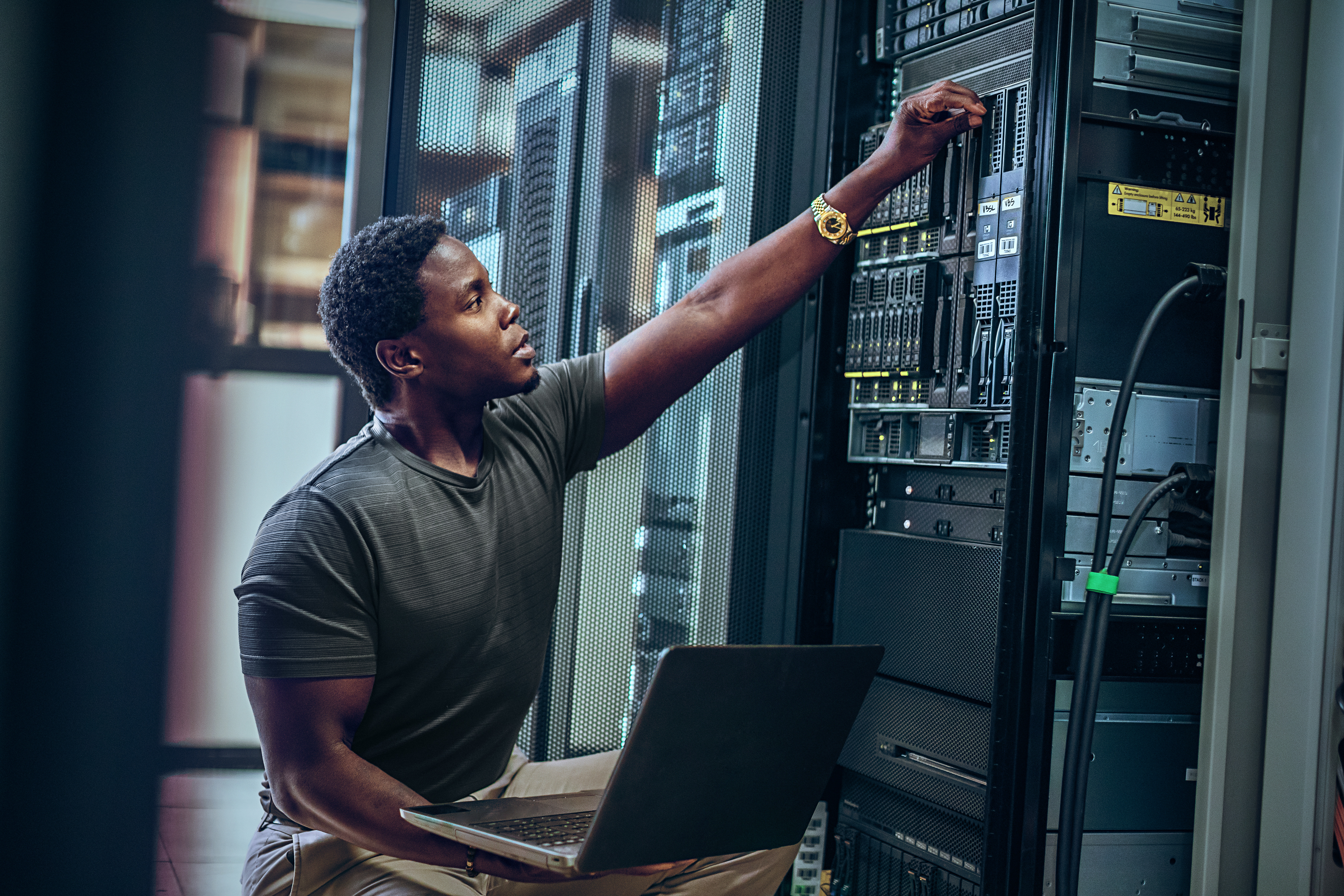 Man in server room with laptop looking at hardware