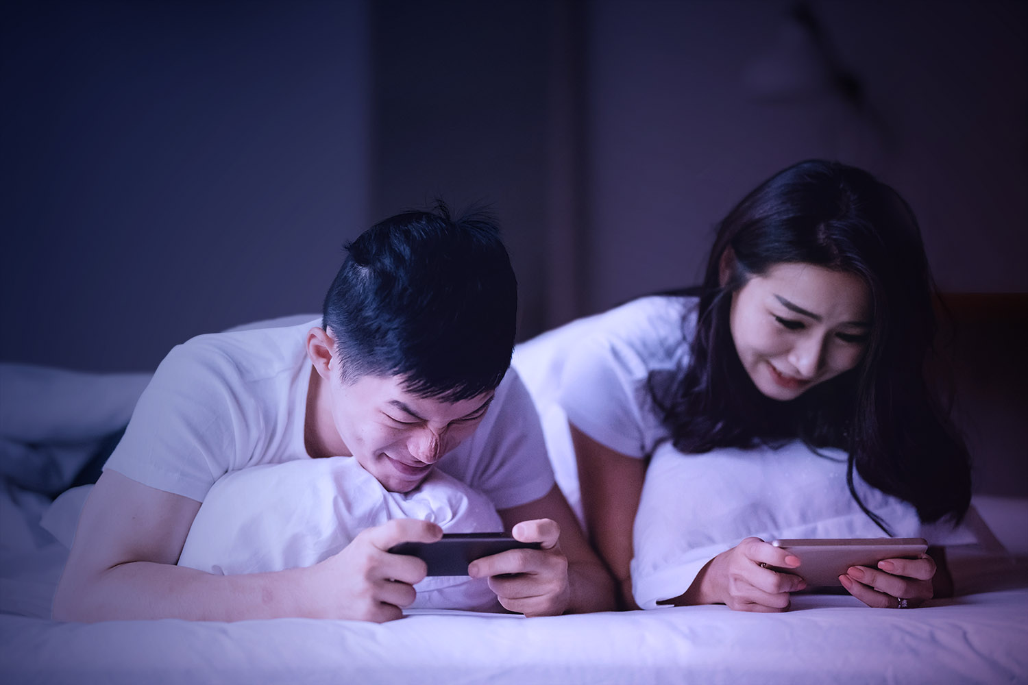 Boy and girl mobile gamers on bed