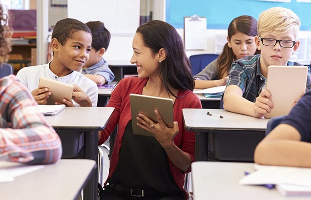 An image depicting a classroom setting with students using tablets for educational purposes. The students are engaged in learning activities, utilizing technology to enhance their education and classroom experience.