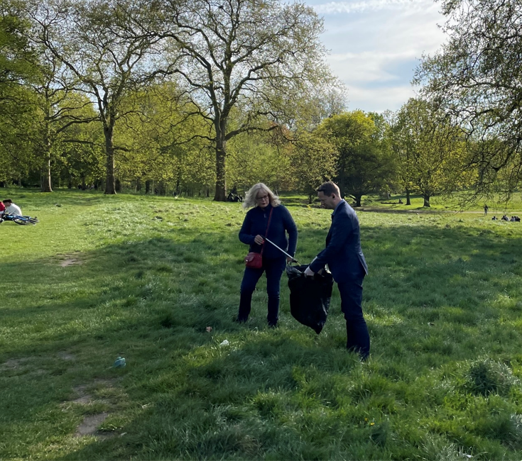 Two people picking up trash from the grass