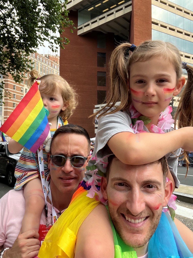 Two young girls on their father's shoulders 