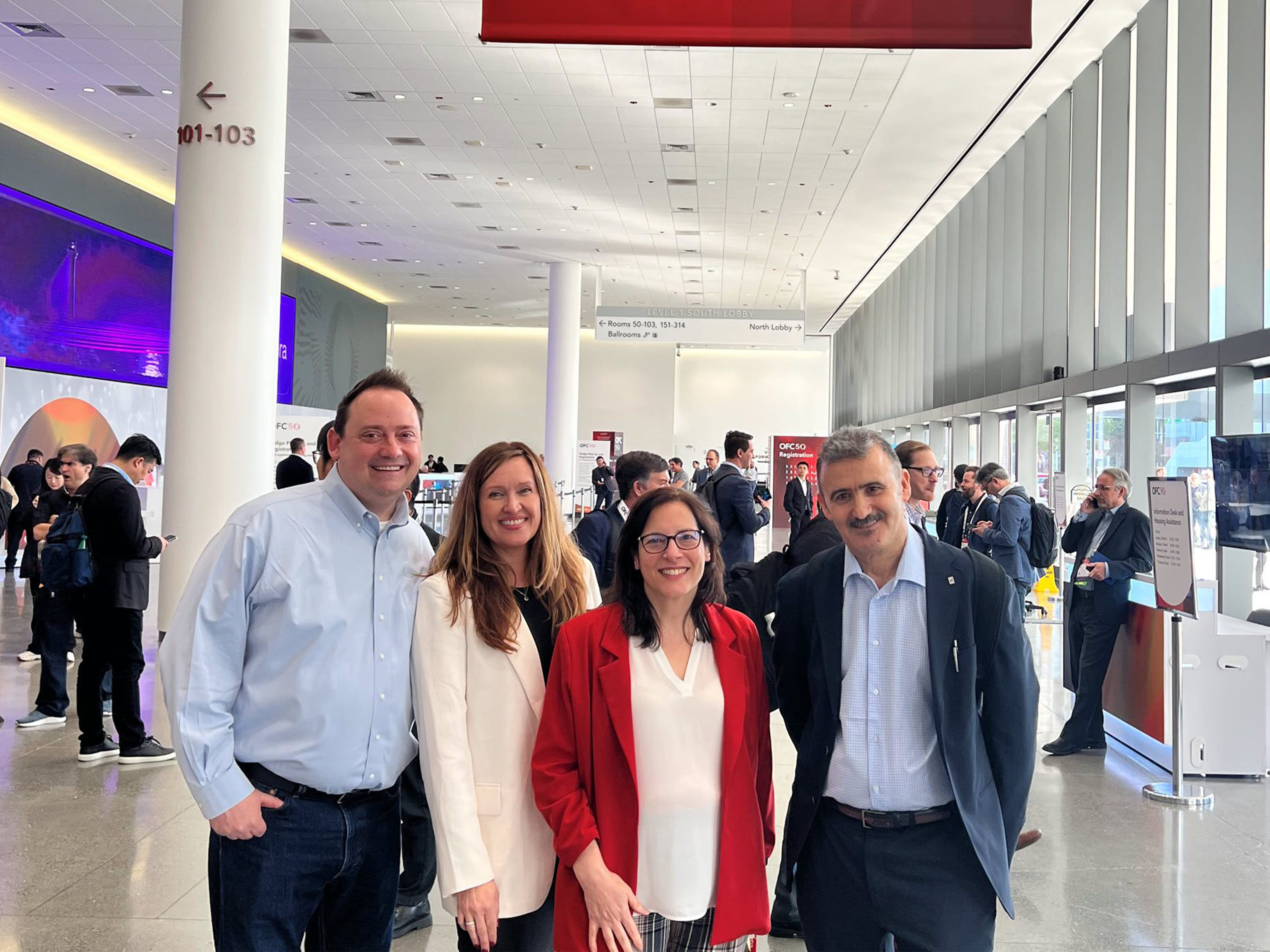 four Ciena employees under a Ciena banner at OFC