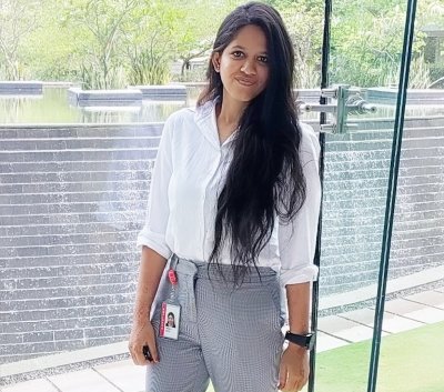 Woman in business attire standing in front of window smiling