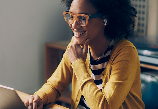 An image of a woman sitting with her laptop, representing the topic of a cybersecurity podcast. The woman is focused on her laptop screen, symbolizing the importance of cybersecurity practices and discussions in the digital age.