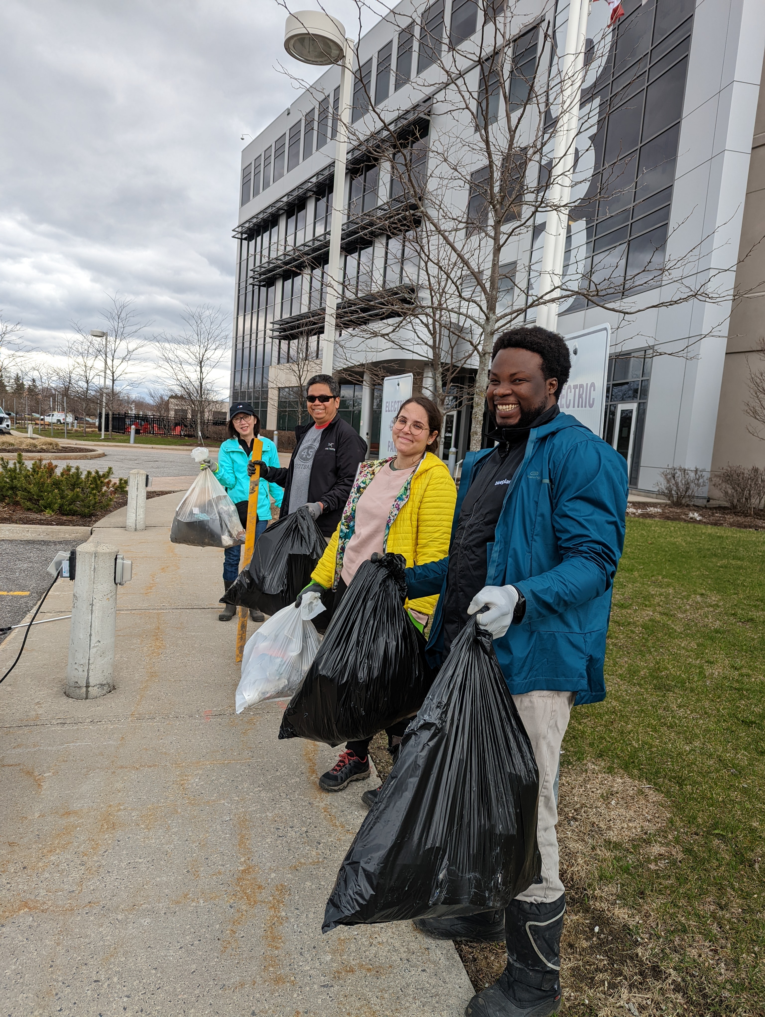 4 people standing with trash bags