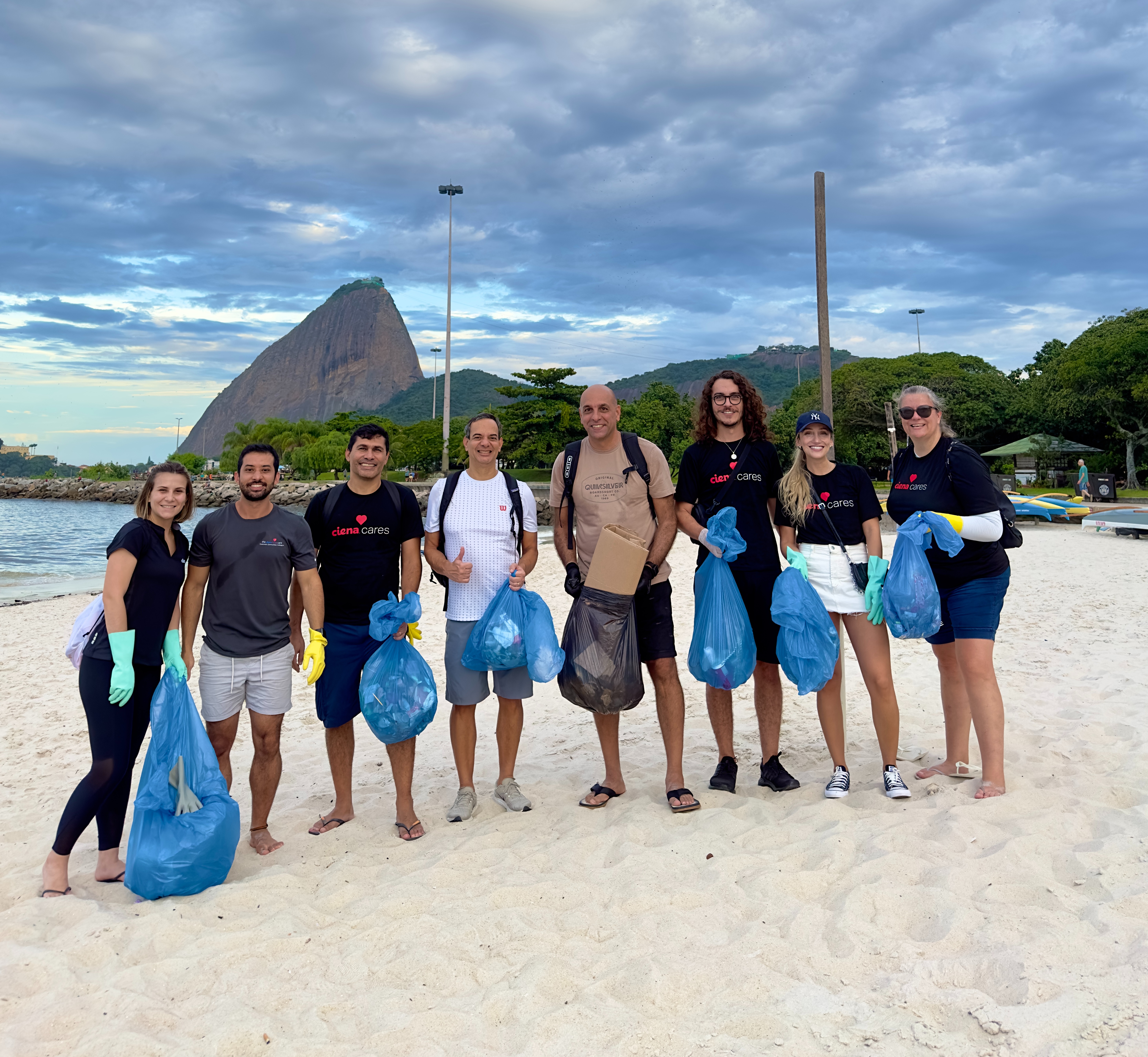 Men and women on a beach with trash bags 