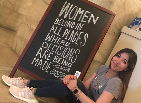 Woman sitting on the floor in front of a sign with a quote on it