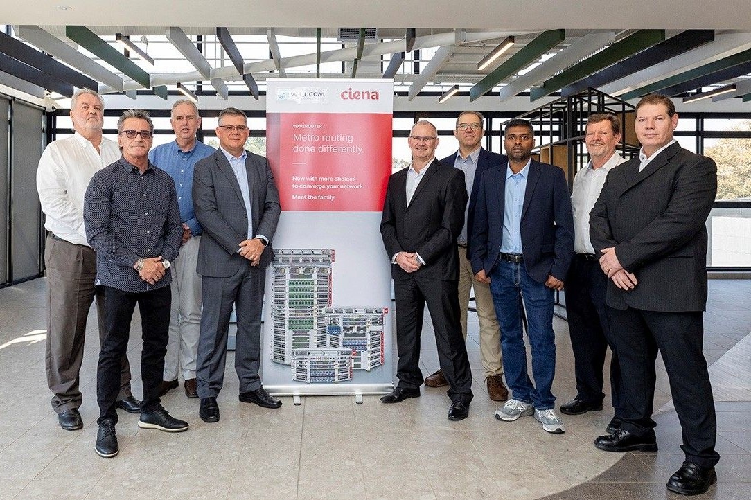 a group of men standing around a Ciena banner
