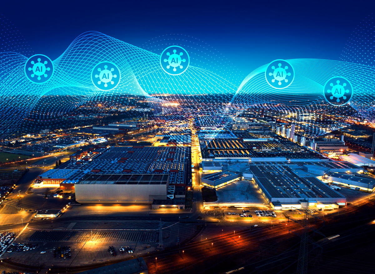 Aerial nighttime view of a smart industrial complex with AI-driven optical networking and digital data flows, illustrating connected data centers, advanced manufacturing, and high-speed network infrastructure.