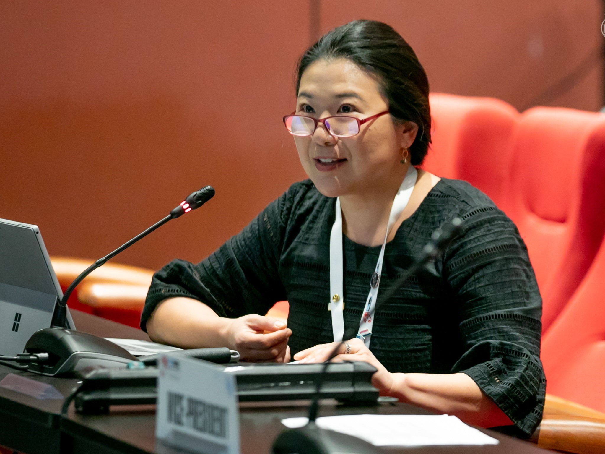 Grace sits at a desk before a microphone