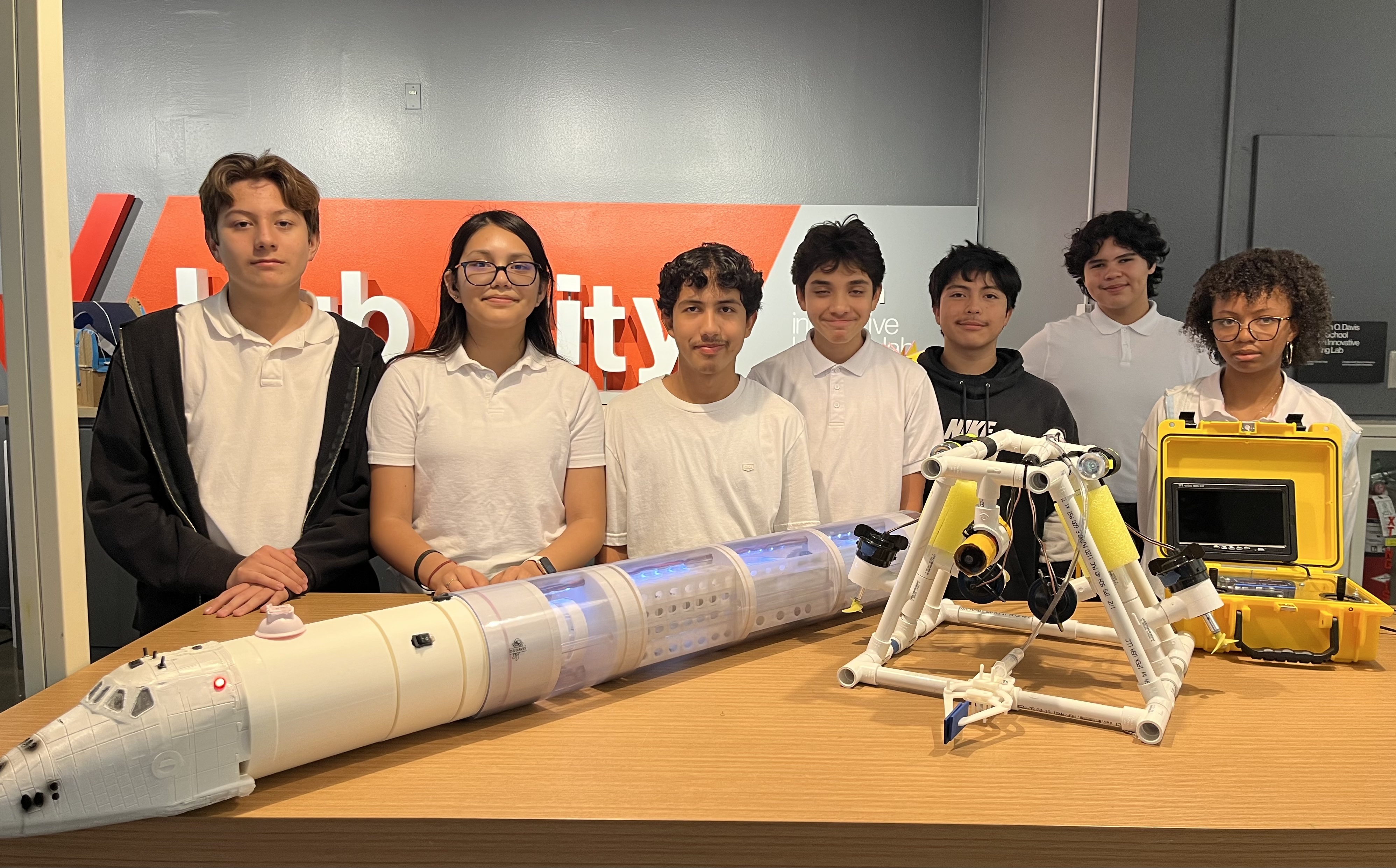 Students standing behind a model spaceship