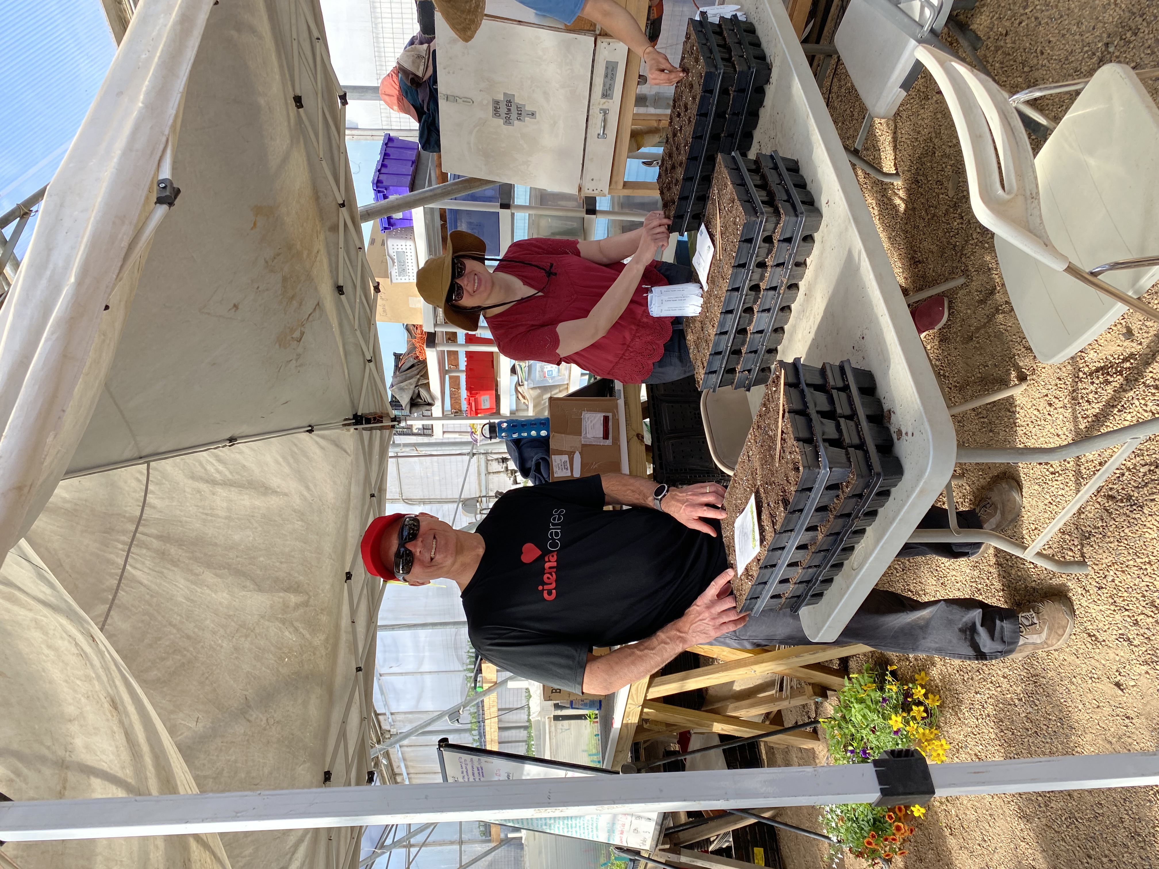 people standing in front of flower pots one with a ciena cares shirt