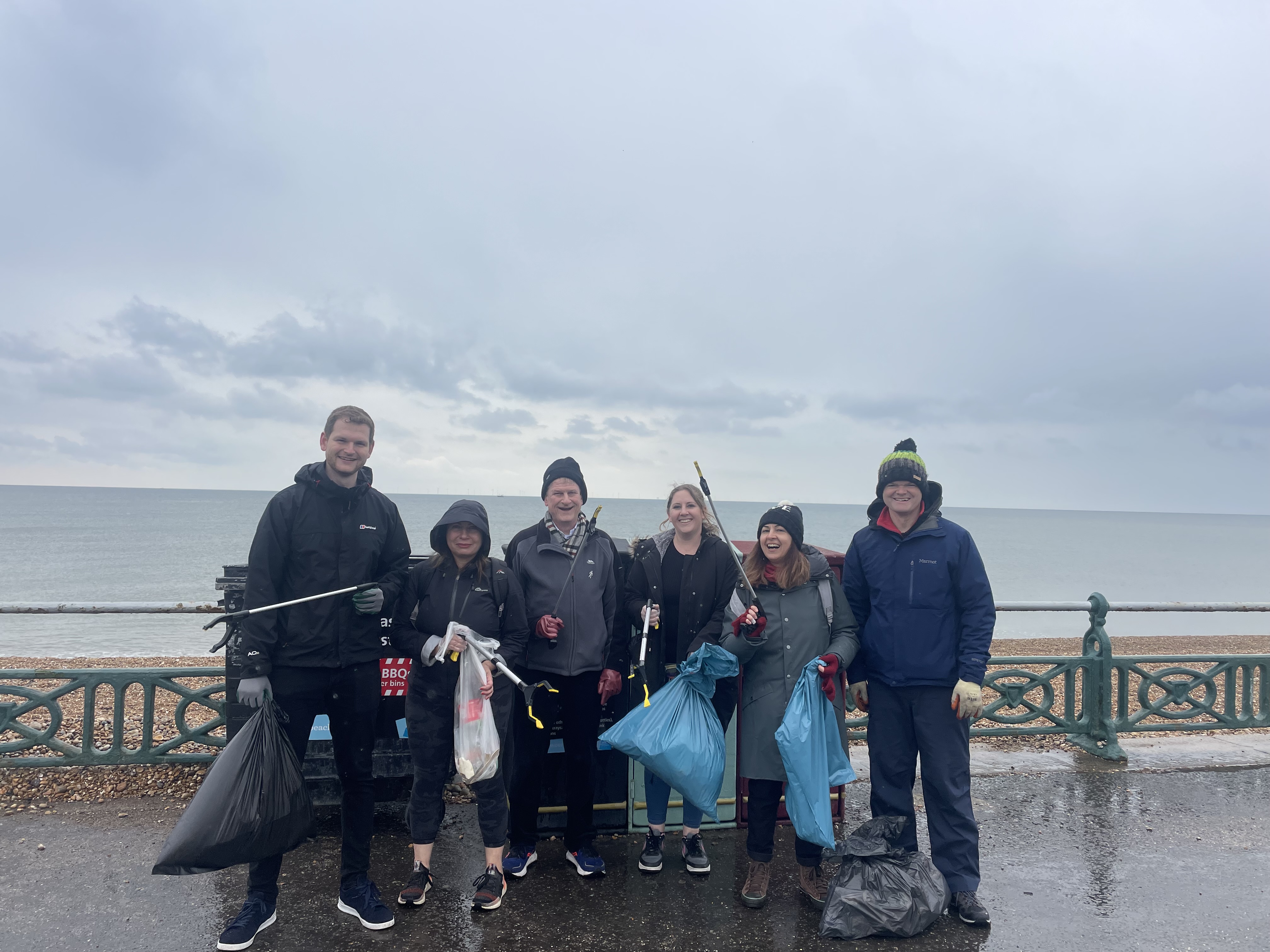 Men and women with trash bags and poles to pick up trash on a beach pier