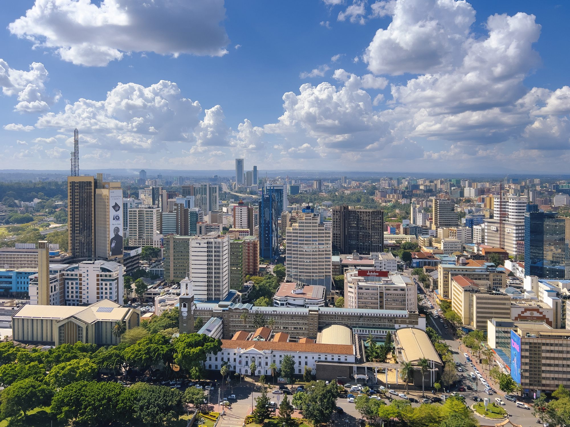 Nairobi skyline with modern high-rise buildings under a bright blue sky with scattered clouds.